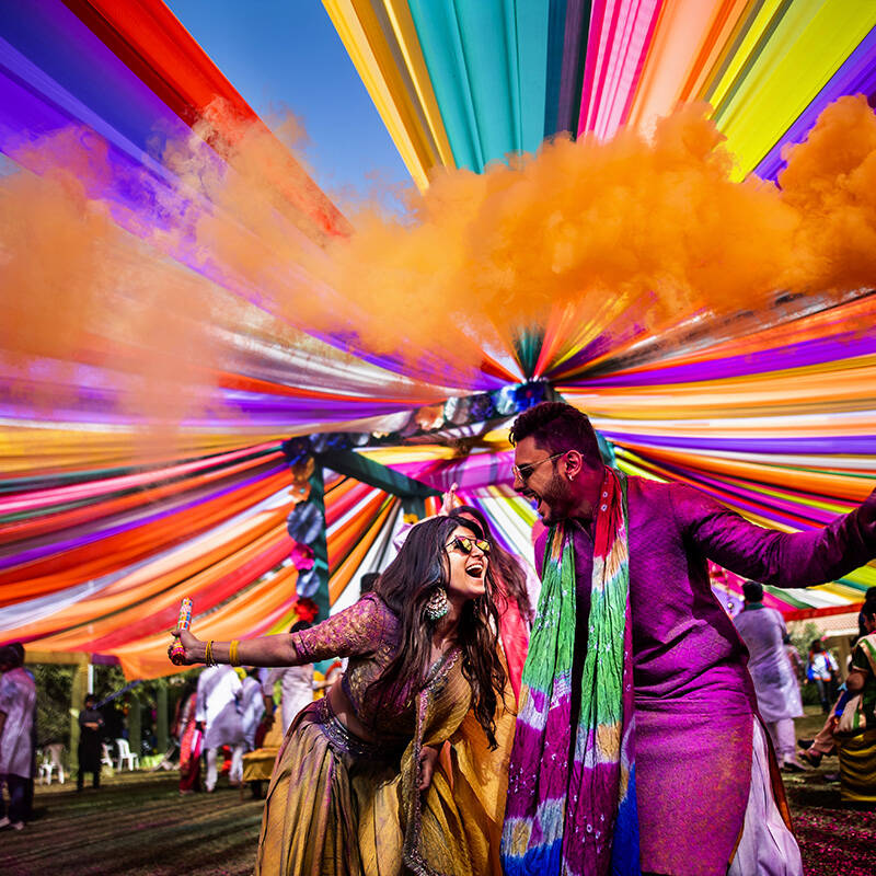 Coppia felice durante un matrimonio colorato sotto un tetto di tessuti multicolori, catturata in uno scatto dinamico e immersivo da Pasquale Minniti.